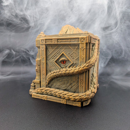 A detailed miniature fantasy treasure chest figurine wrapped in thick rope, featuring a single red eye on the front panel, set against a smoky gray background.